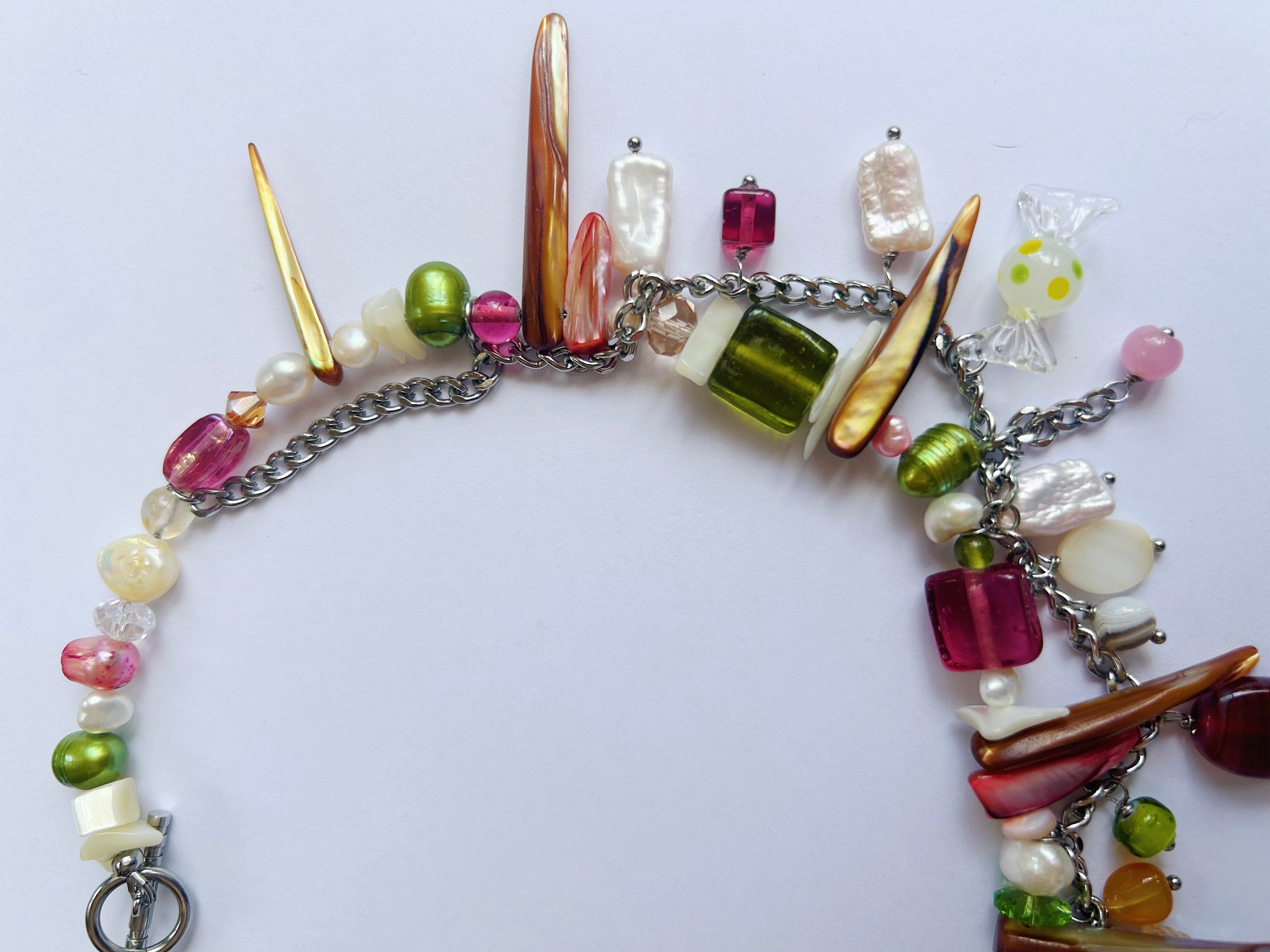 Colorful beaded necklace with various beads and a metal chain on a white background